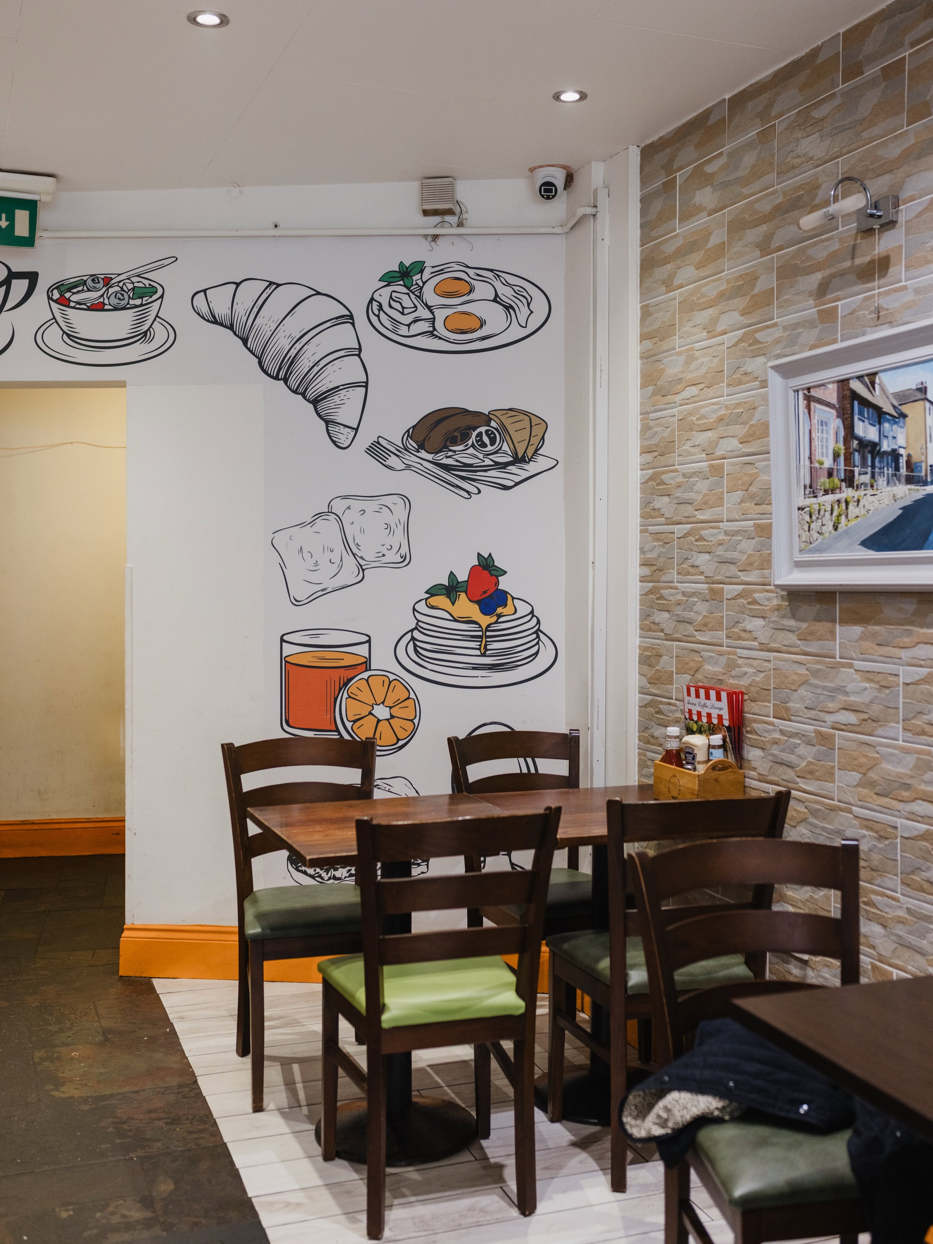 Aroma’s indoor wooden tables and chairs beside its distinctive breakfast and coffee wall drawings